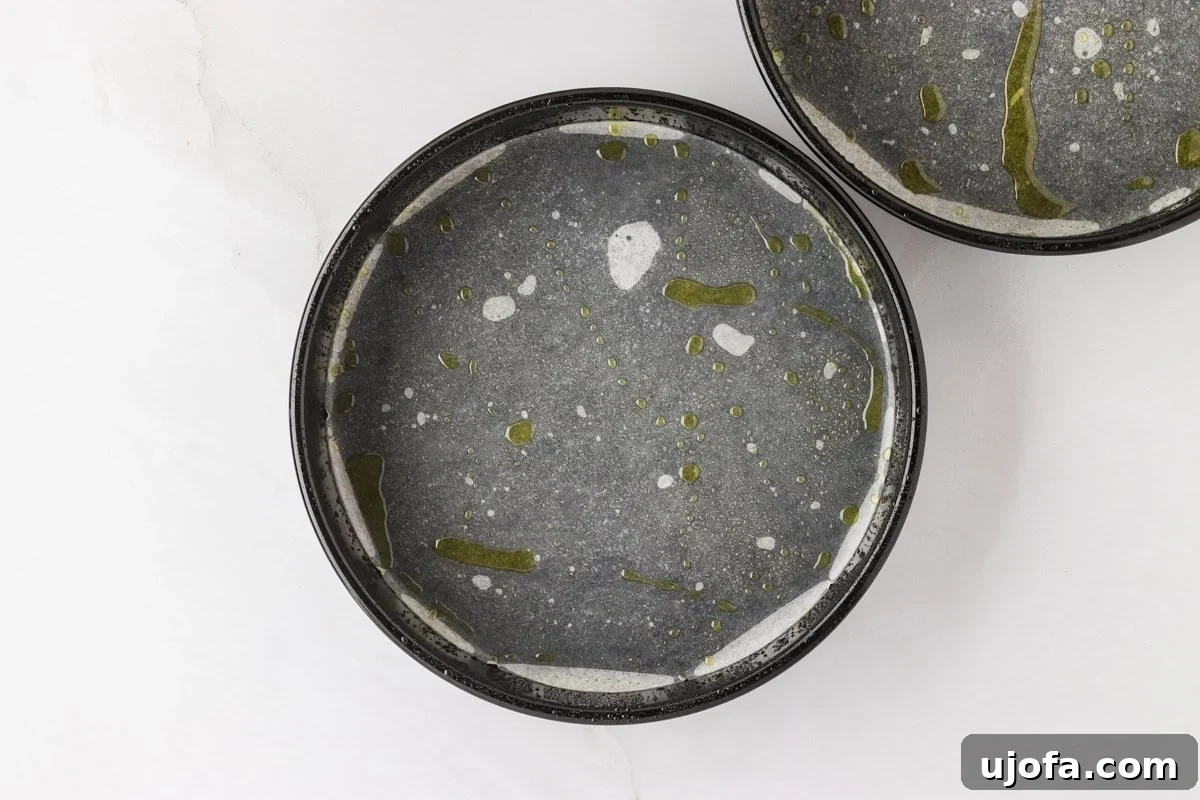 A round cake pan lined with parchment paper and greased, ready for the carrot cake batter.