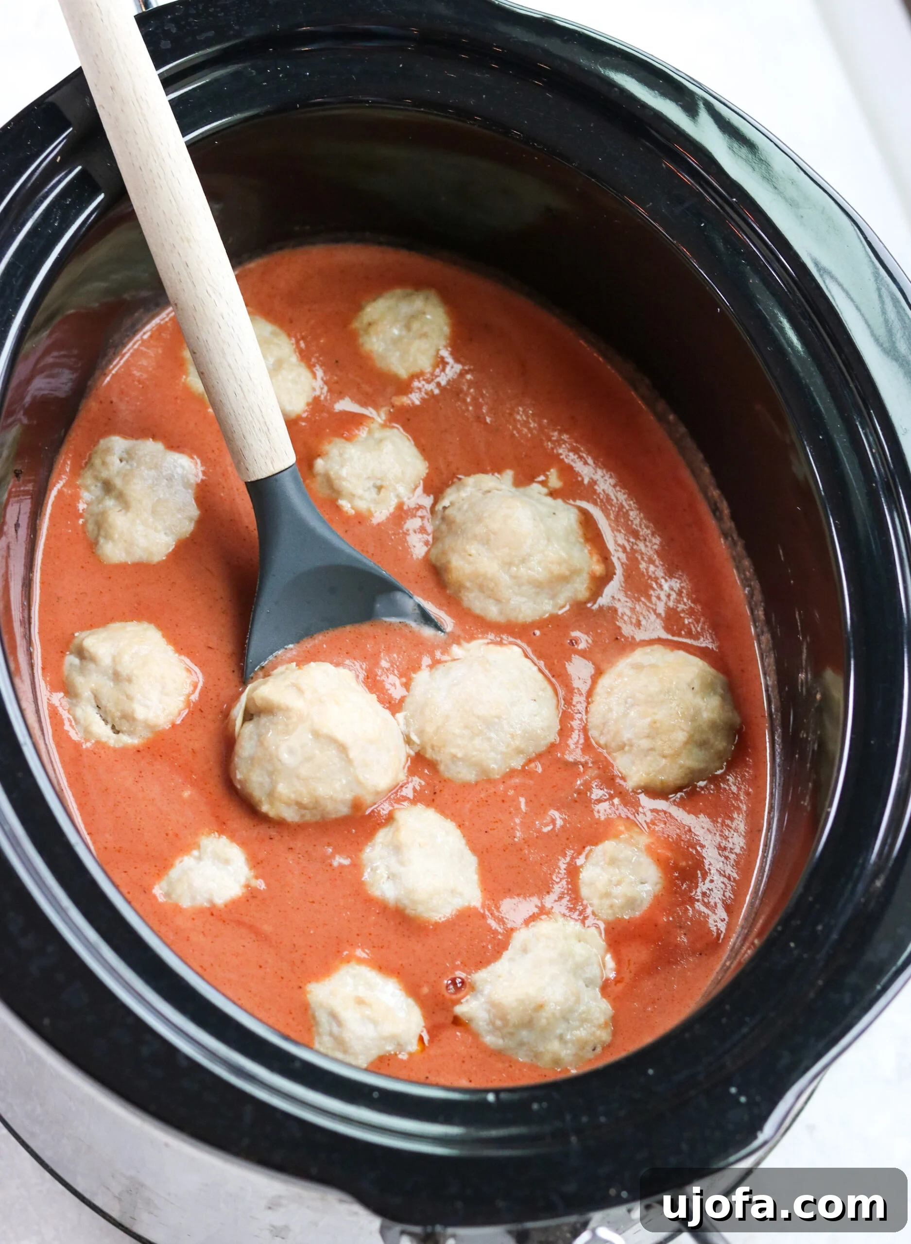 Paleo Butter Chicken Meatball Bake 4 healthy chicken meatballs with creamy tomato curry sauce in a black slow cooker