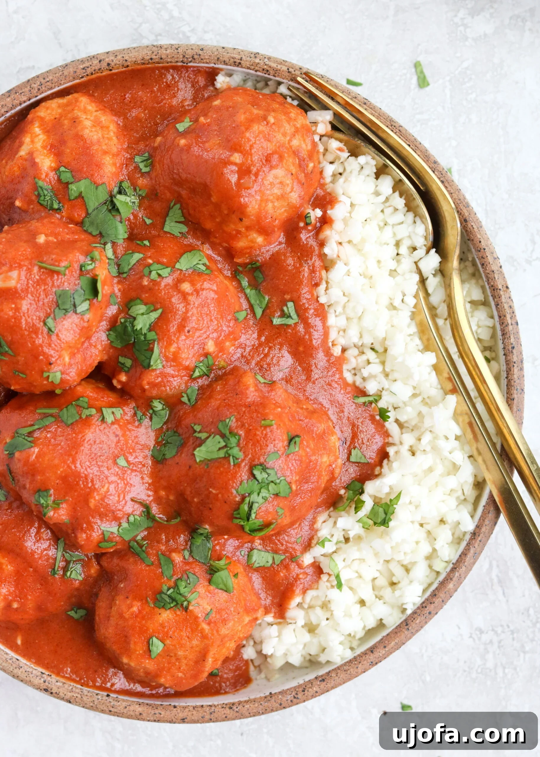 Paleo Butter Chicken Meatball Bake 5 Creamy Garam Masala Curry Sauce with Ground Chicken Meatballs served over cauliflower rice in a bowl with two gold forks