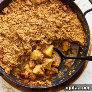 Gluten-free apple crisp, with a golden oat topping and bubbly filling, served in a square baking dish.
