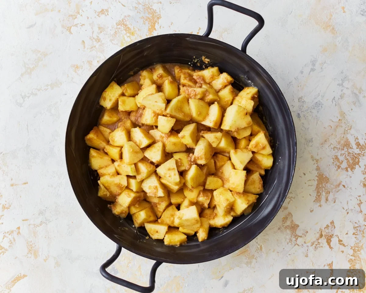 Gluten-free apple crisp filling evenly spread in a greased glass baking dish, ready for the topping.