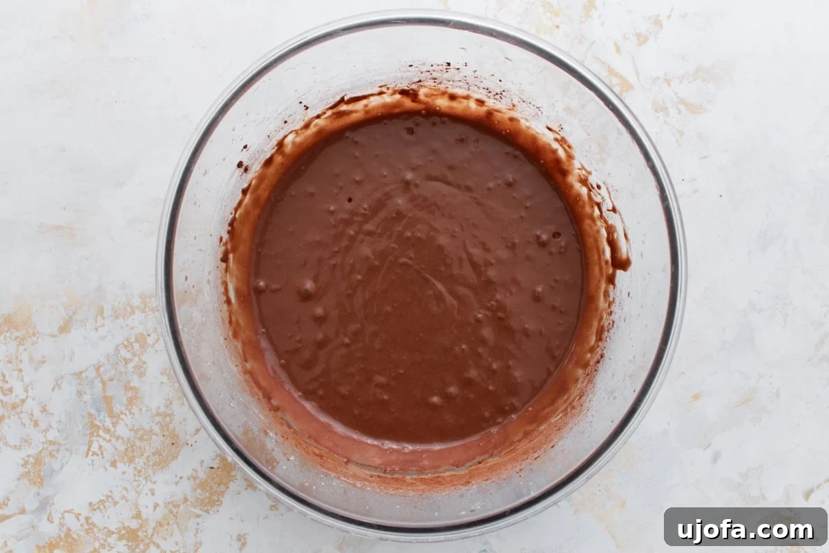 Guilt-Free Chocolate Indulgence 10 Glossy, pourable chocolate batter in a bowl after boiling water is added, with bubbles forming on the surface.