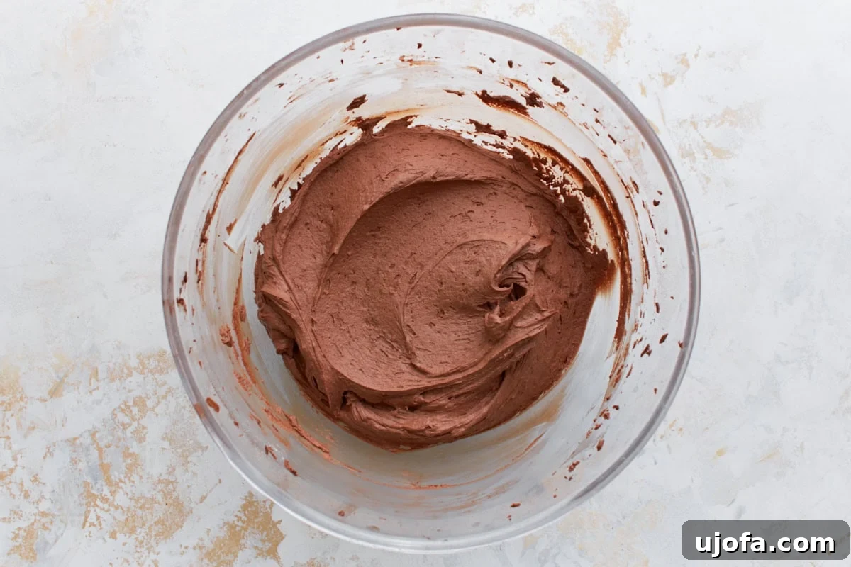Guilt-Free Chocolate Indulgence 17 Fluffy, fully mixed chocolate buttercream frosting in a glass bowl, ready for piping onto cupcakes.