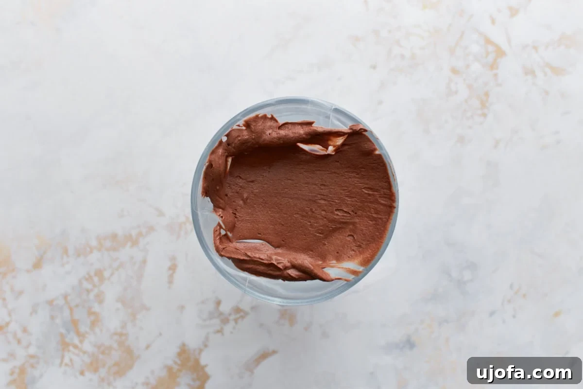 Guilt-Free Chocolate Indulgence 18 Overhead view of chocolate frosting scooped neatly into a piping bag set inside a tall cup for easy filling.