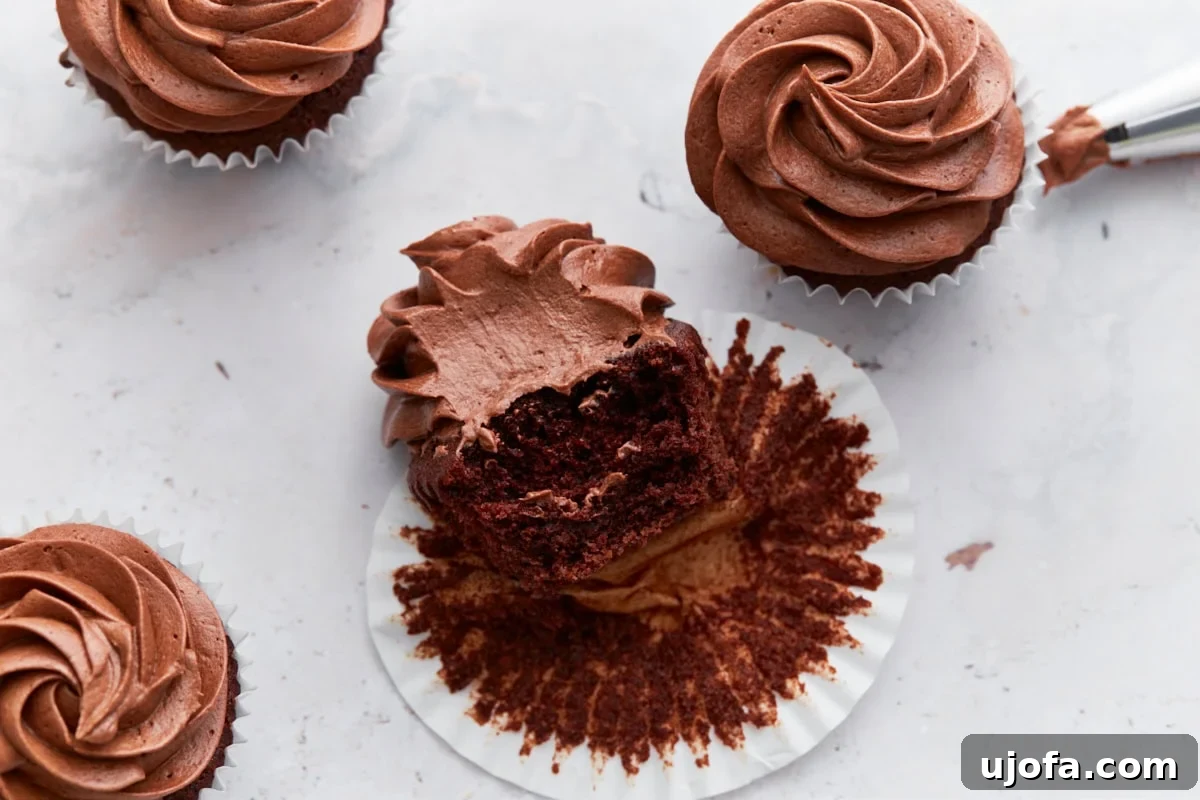Guilt-Free Chocolate Indulgence 20 Close-up of a chocolate cupcake with a bite taken out, revealing a moist interior and fluffy chocolate frosting, surrounded by more frosted cupcakes.