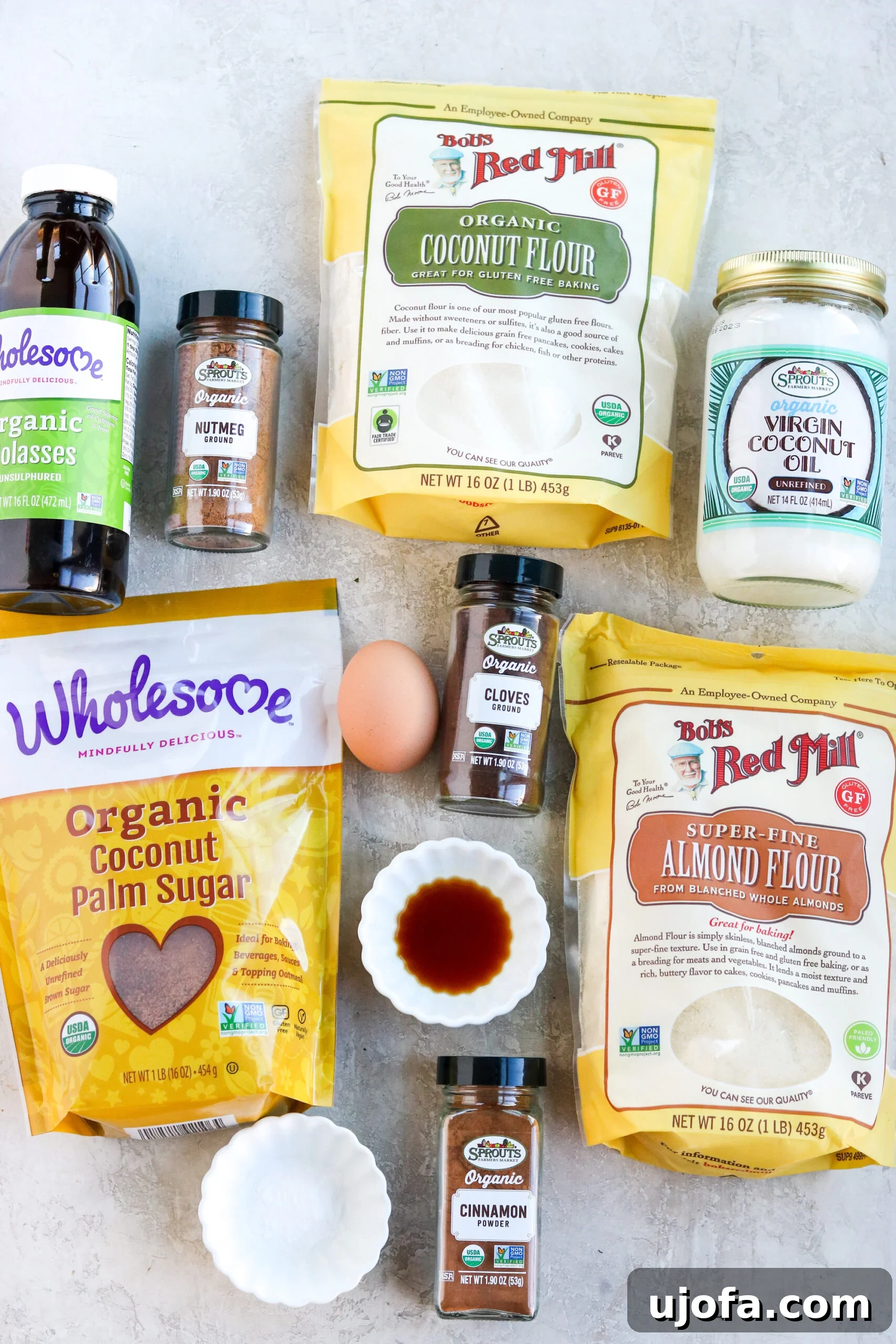 Simple Gluten Free Almond Flour Gingersnaps 3 A collection of ingredients laid out, including almond flour, coconut oil, molasses, spices, and an egg