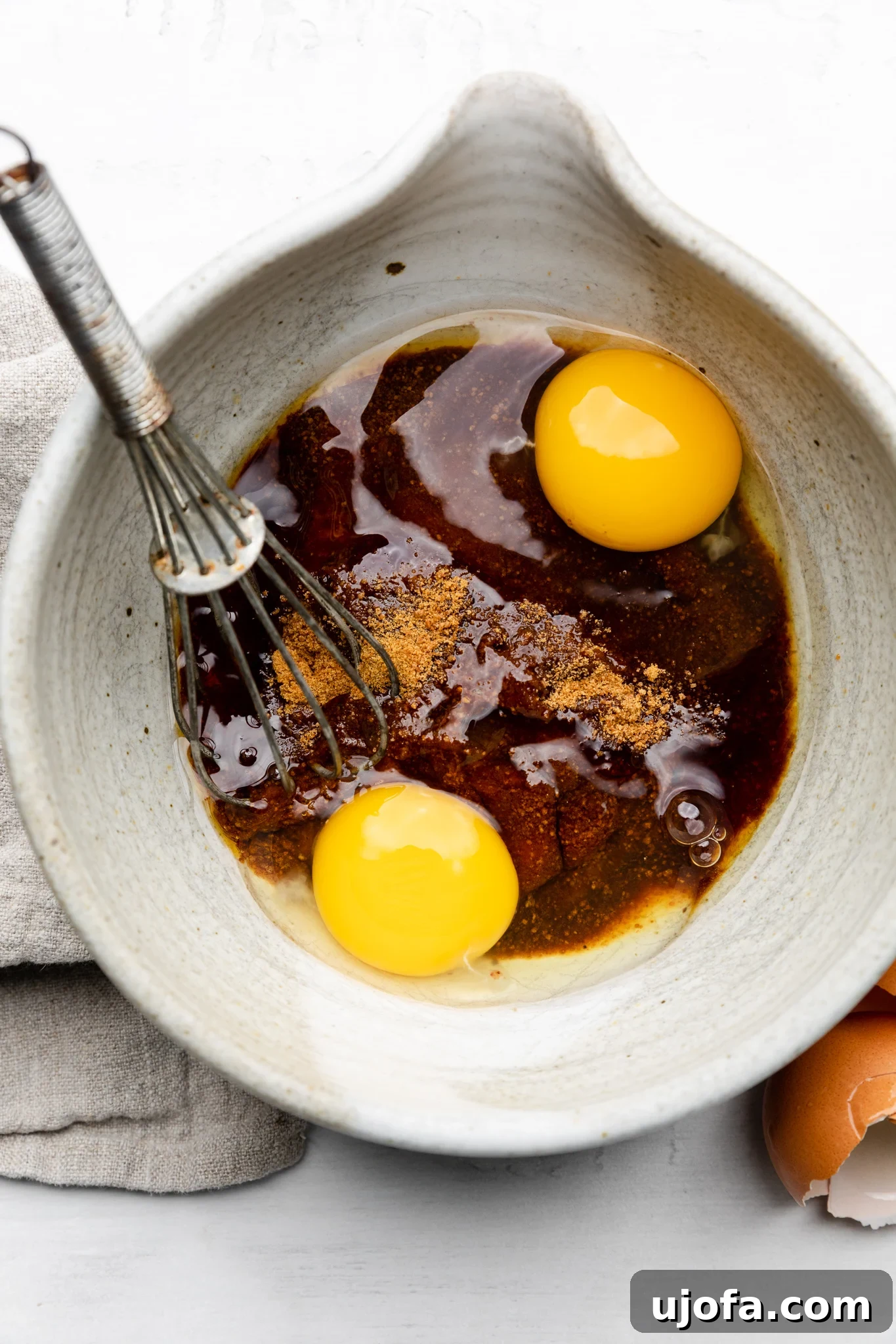 Gluten Free Molten Chocolate Lava Bites 4 Eggs, maple syrup, coconut sugar, and vanilla being whisked together in a mixing bowl.