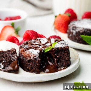 Gluten Free Molten Chocolate Lava Bites 8 mini chocolate lava cake on a plate with mint leaves and raspberries and strawberries in the background