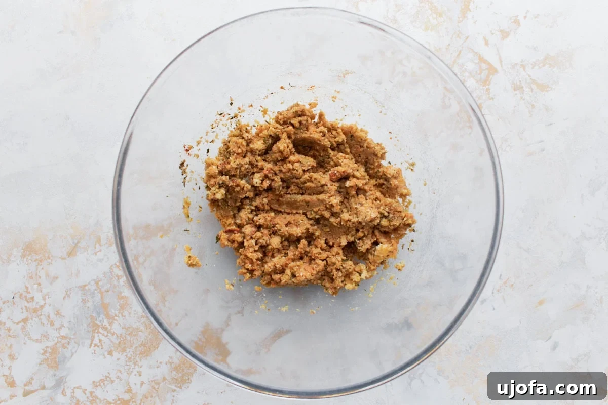 A mixing bowl containing a crumbly breadcrumb mixture, part of the preparation process for gluten-free meatloaf.
