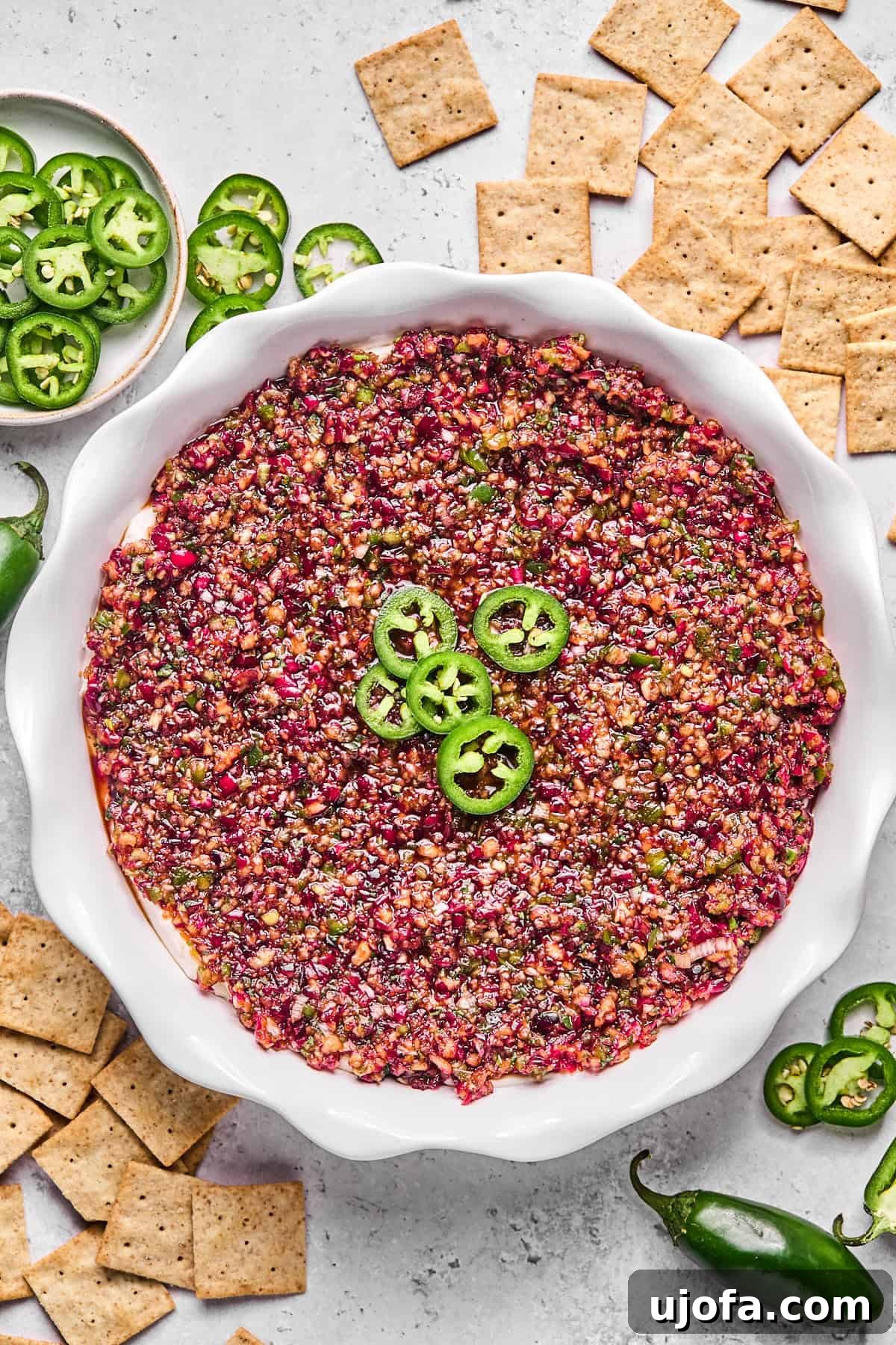 Effortless Dairy Free Cranberry Jalapeno Dip 10 cranberry jalapeno cream cheese dip in a pie plate surrounded by crackers and jalapenos