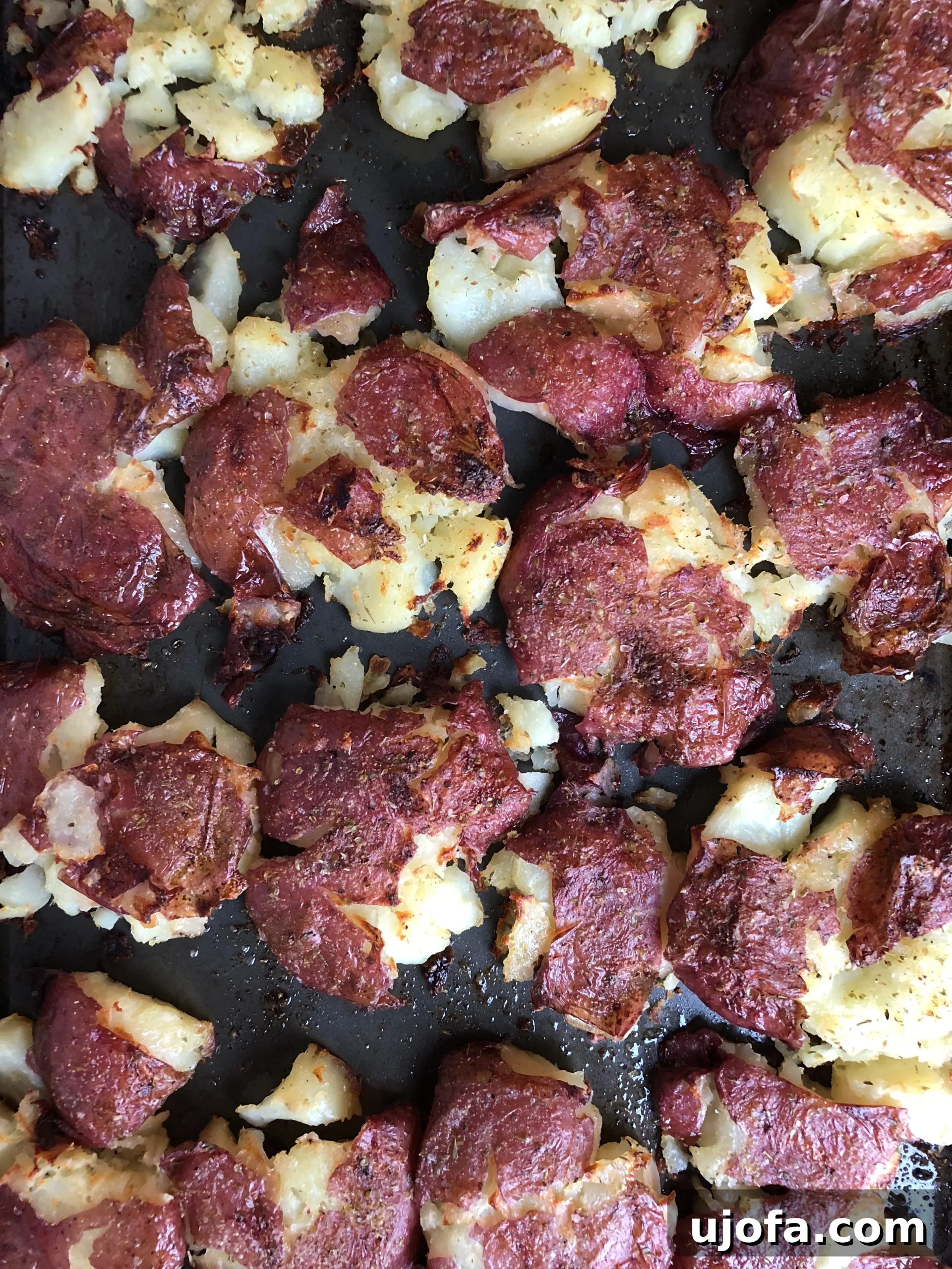 Close-up view of a tray of crispy smashed potatoes, showing the perfectly browned edges