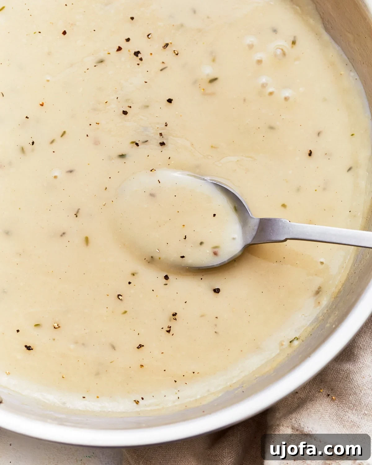 Overhead view of a spoon scooping gluten-free gravy from a pan, ready to be served.