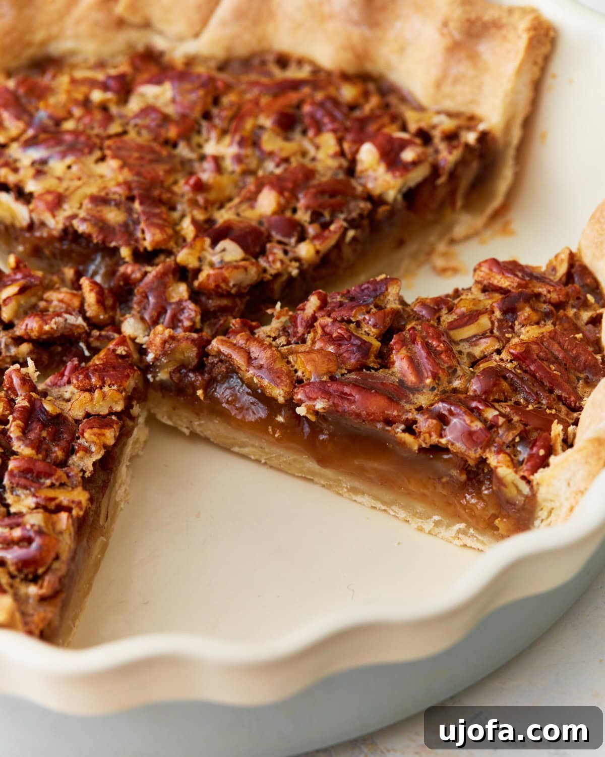 Side view of a perfectly baked gluten-free pecan pie, showcasing its golden crust and rich, nutty filling in a pie dish.