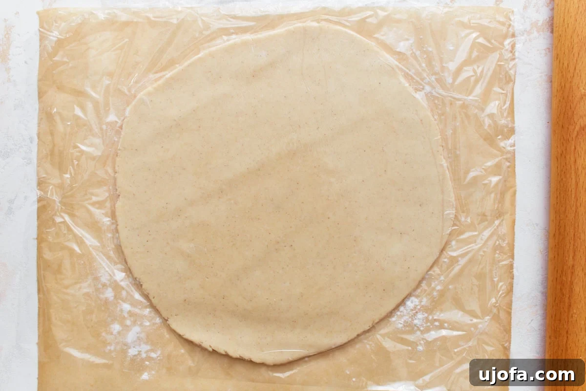 A rolled-out circle of gluten-free pie crust dough on a floured surface, thin and ready for the pie pan.