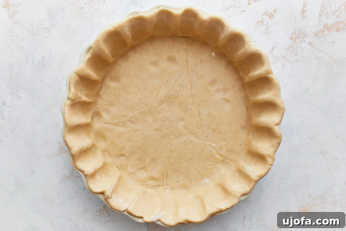A gluten-free pie crust neatly pressed into a pie pan, showing the crimped edges and ready for filling.