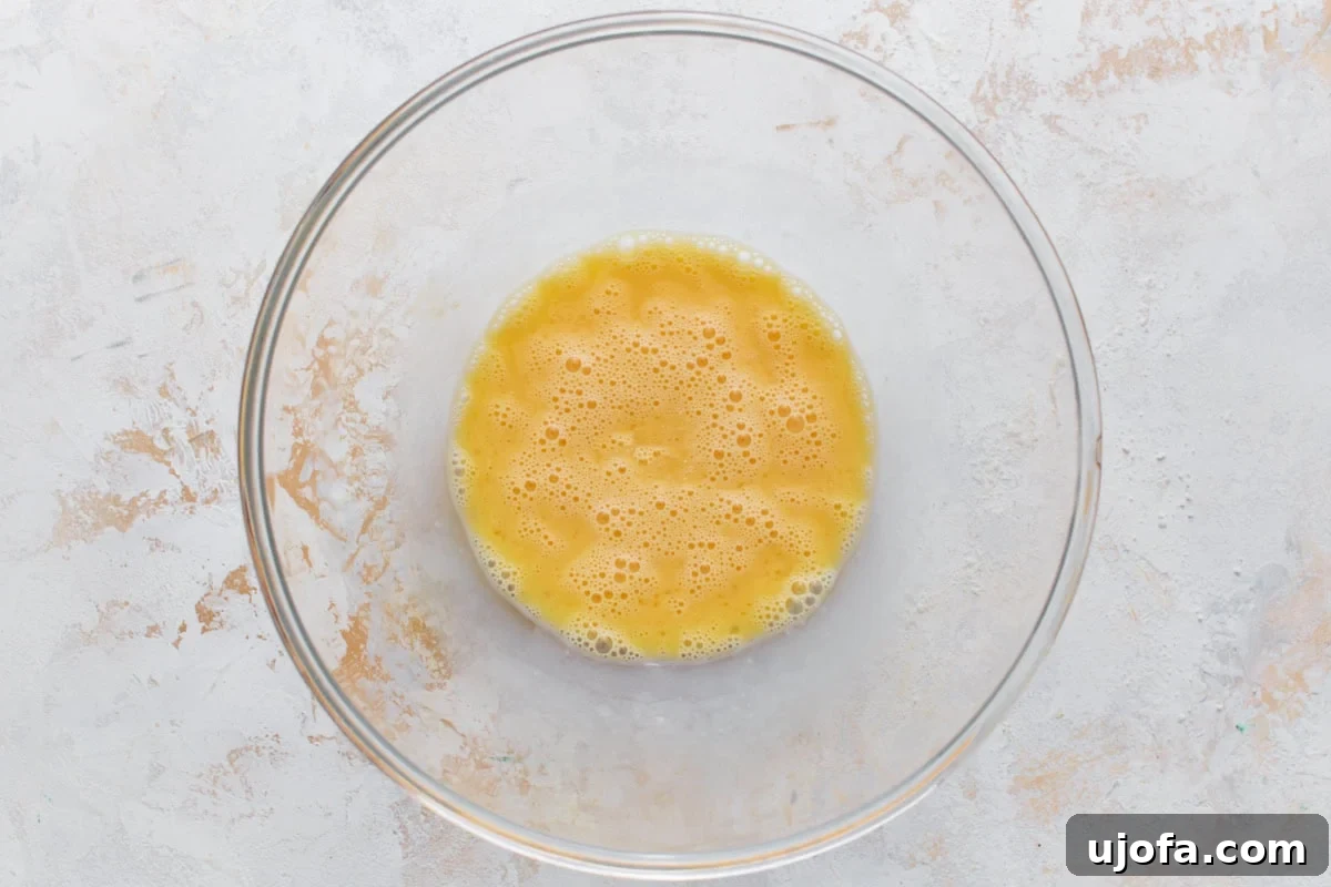 Three whisked large eggs in a clear glass bowl, smooth and ready for the pecan pie filling mixture.
