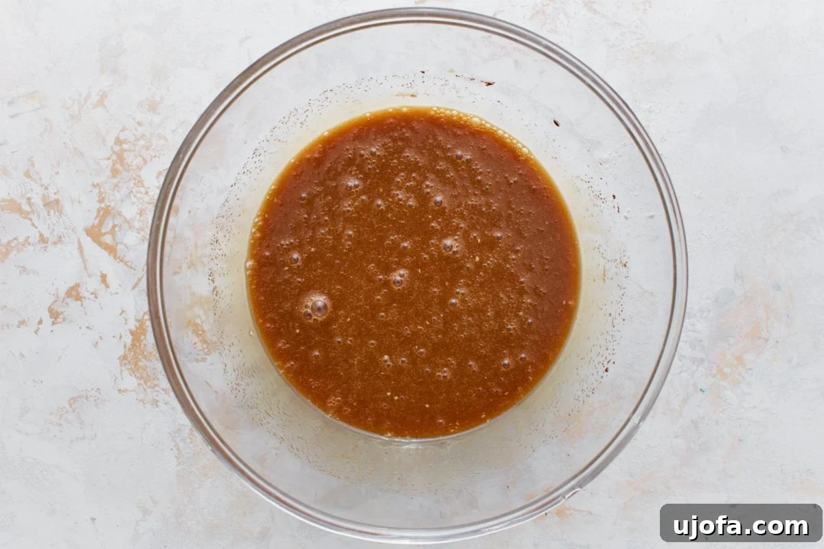 The combined gluten-free pecan pie filling mixture in a glass bowl, smooth and glossy with a rich caramel color.