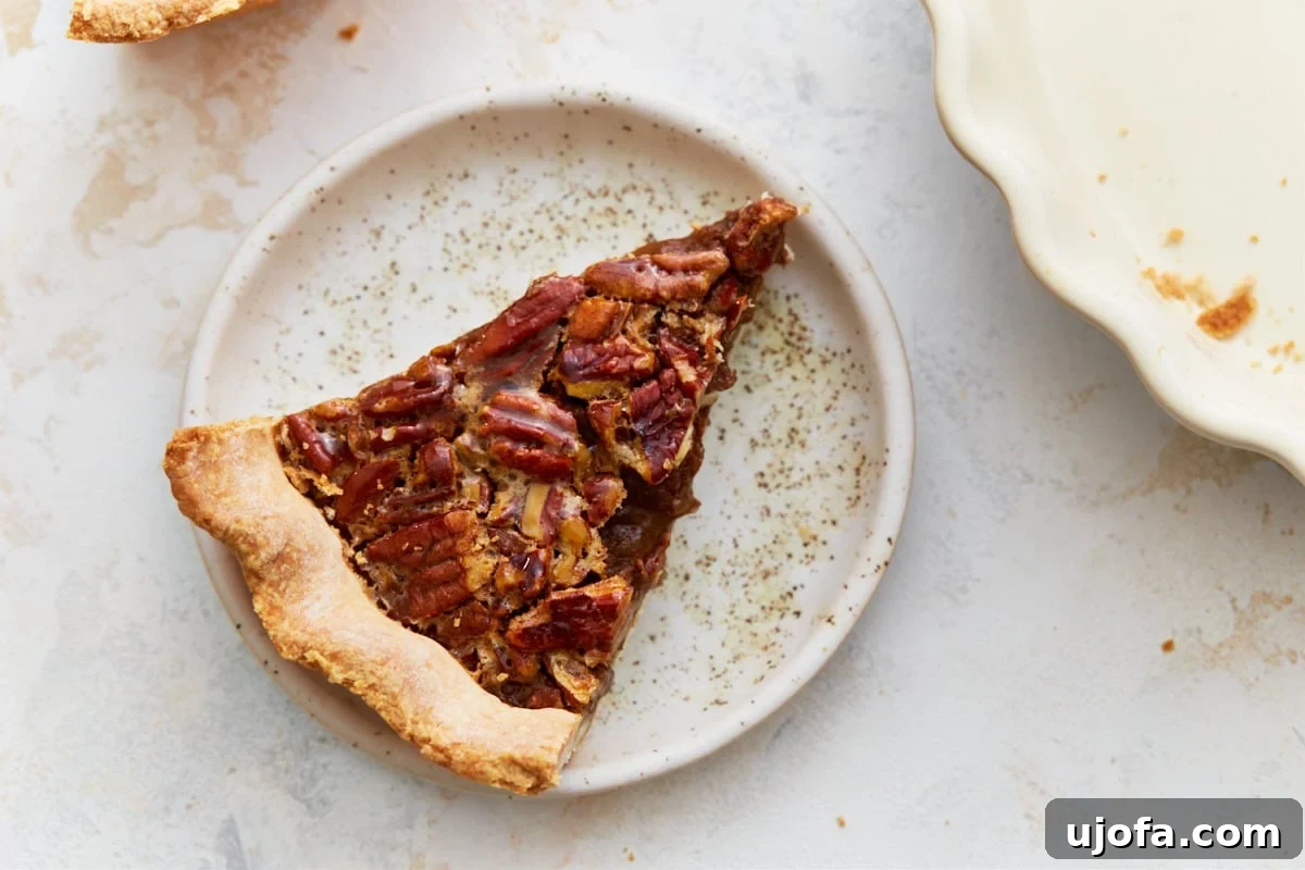 Overhead view of a perfectly baked slice of gluten-free pecan pie on a white plate, ready to be enjoyed.