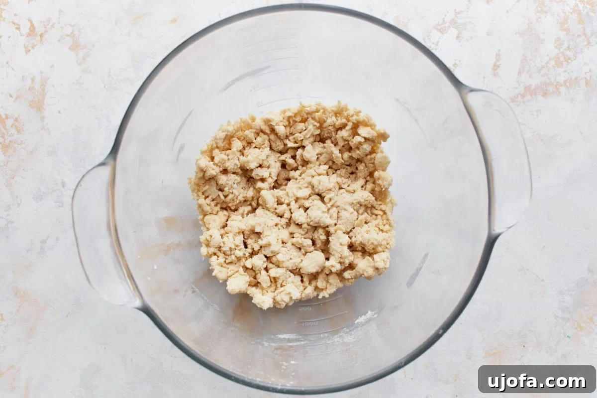 Gluten-free flour mixed with cold butter and shortening in a glass mixing bowl, showing crumbly texture.