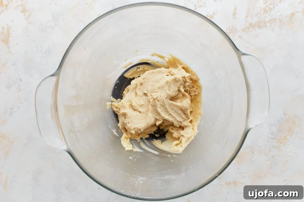 Gluten-free pie crust dough beginning to form in a glass mixing bowl after wet ingredients are added.