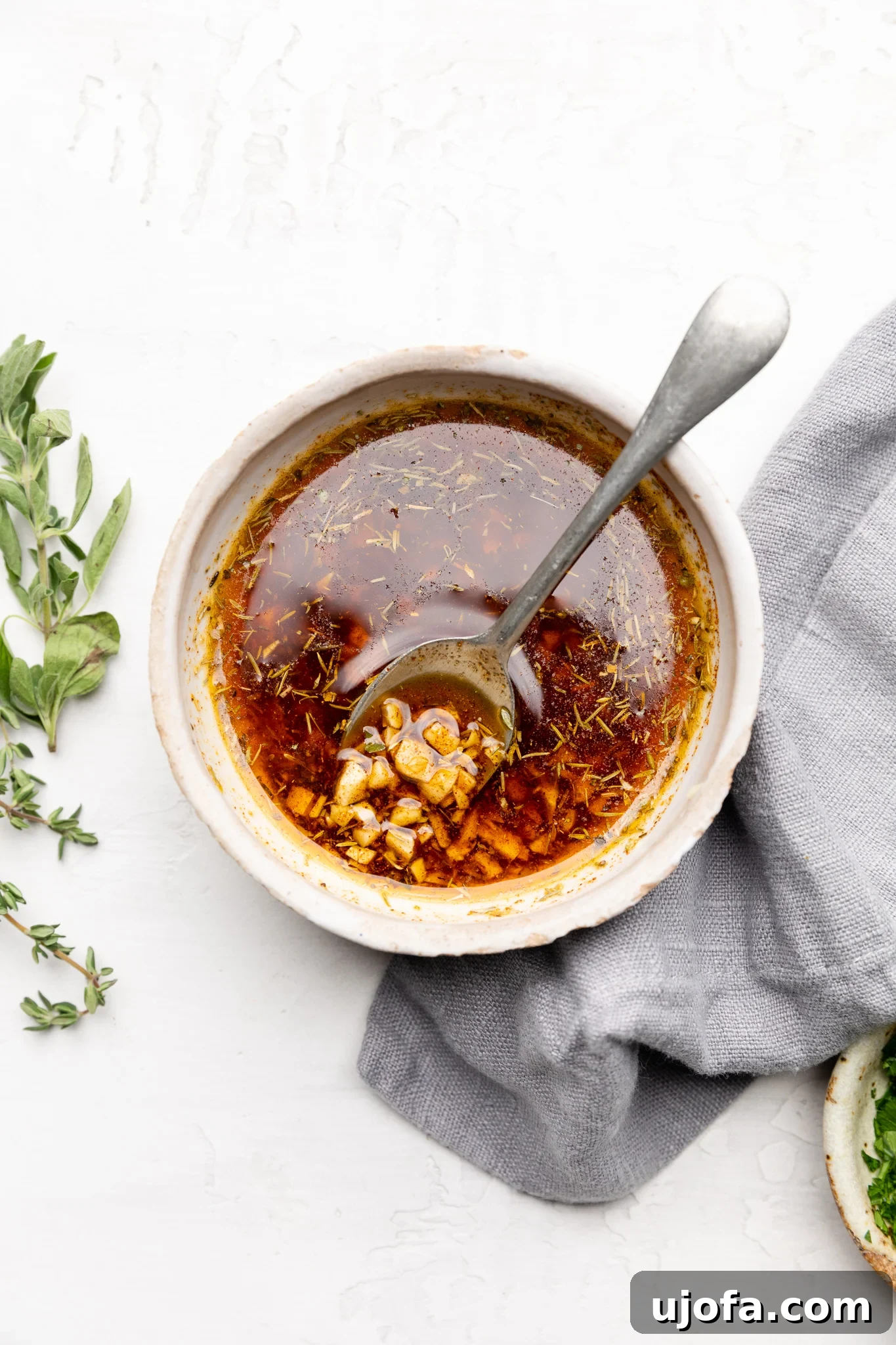A bowl of vibrant orange Cajun butter sauce with a silver spoon, showcasing its rich texture