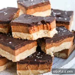 Vegan gluten free millionaire shortbread bars stacked on a plate. One has a bite out of it
