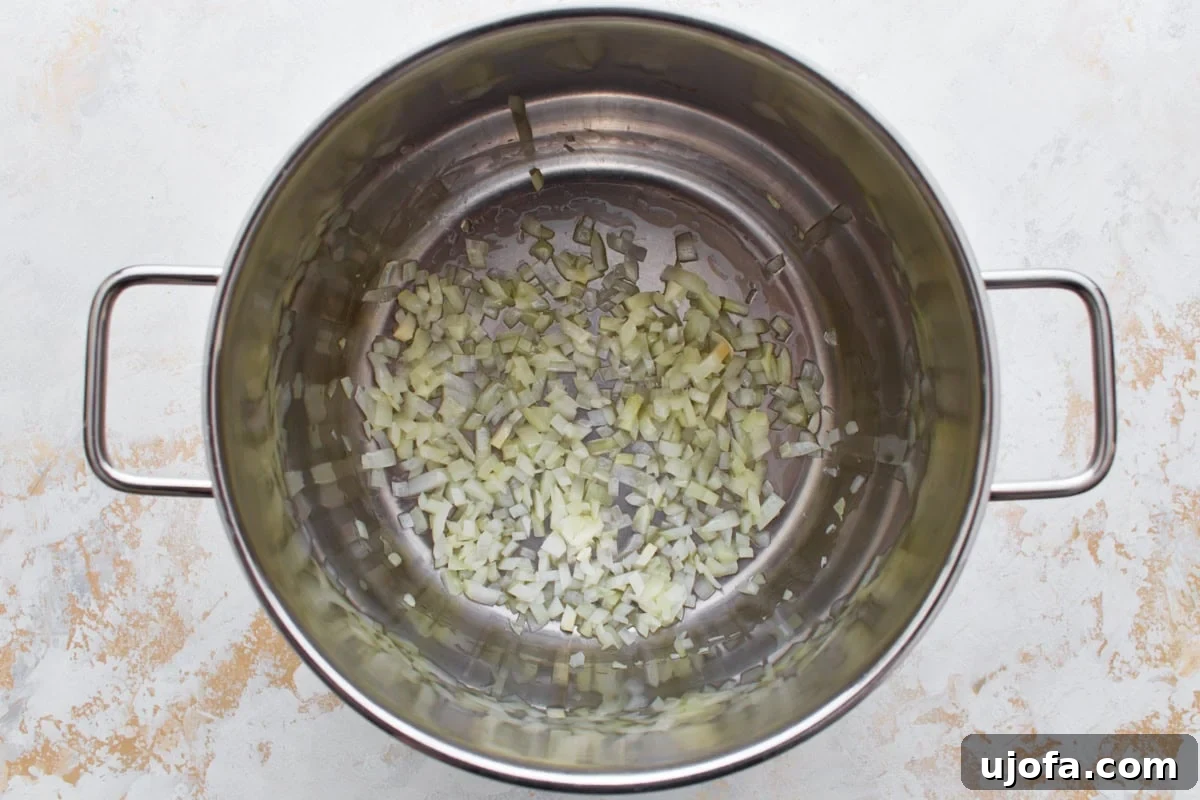 Diced onions sautéing in a large stainless steel pot.