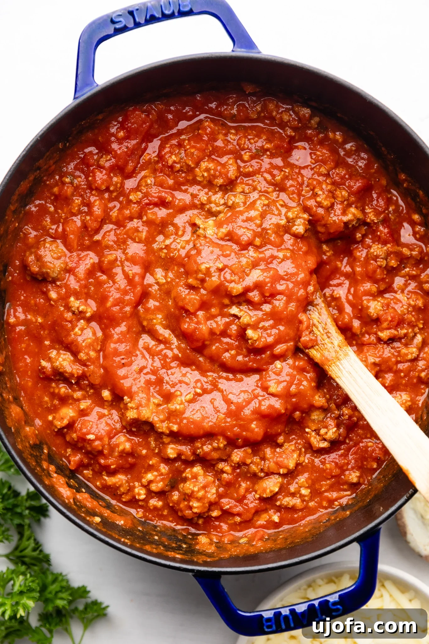Rich meat sauce simmering in a blue Staub dutch oven, ready for gluten-free lasagna