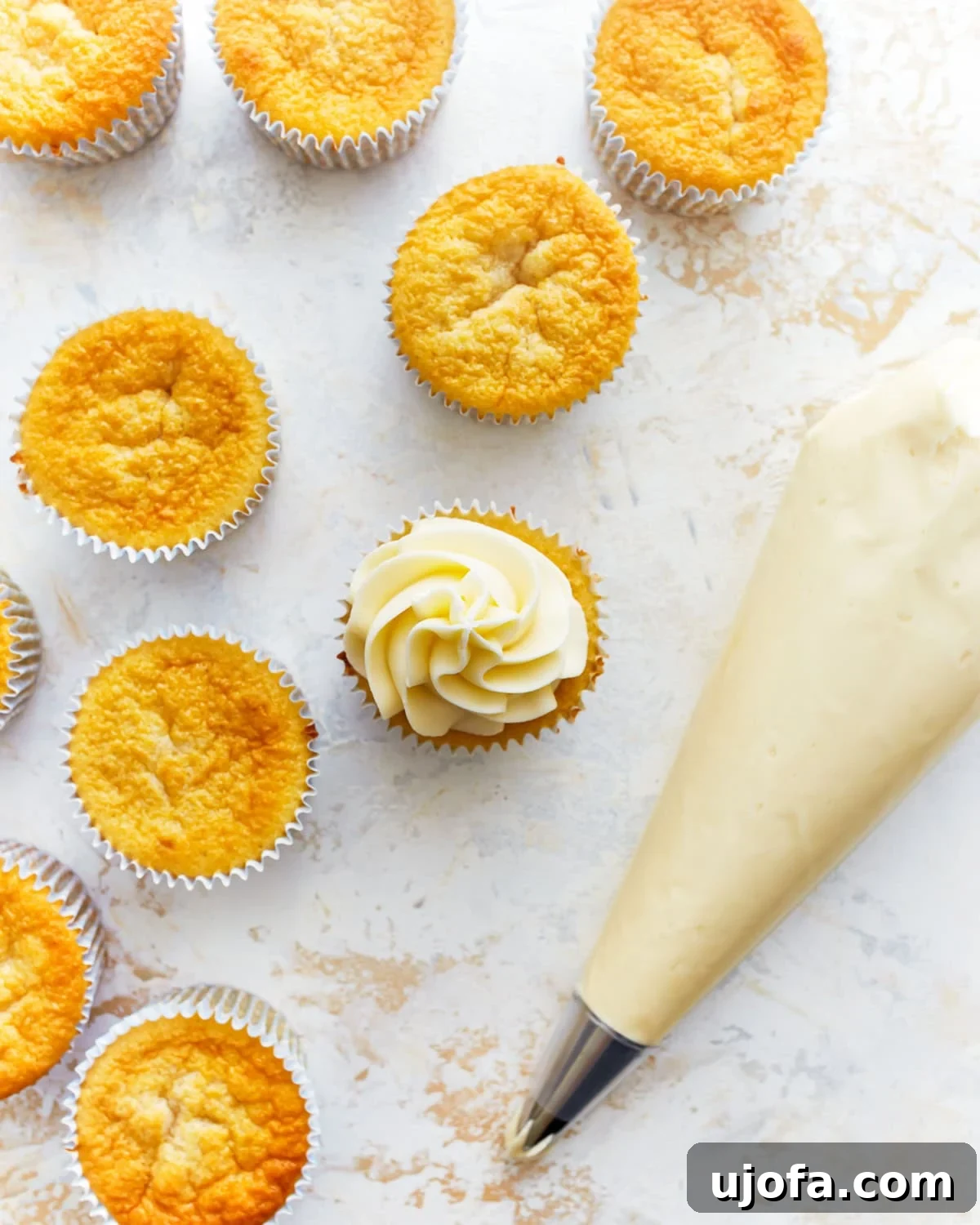 Close-up of fluffy gluten-free vanilla cupcakes being decorated with perfectly piped vanilla buttercream frosting.
