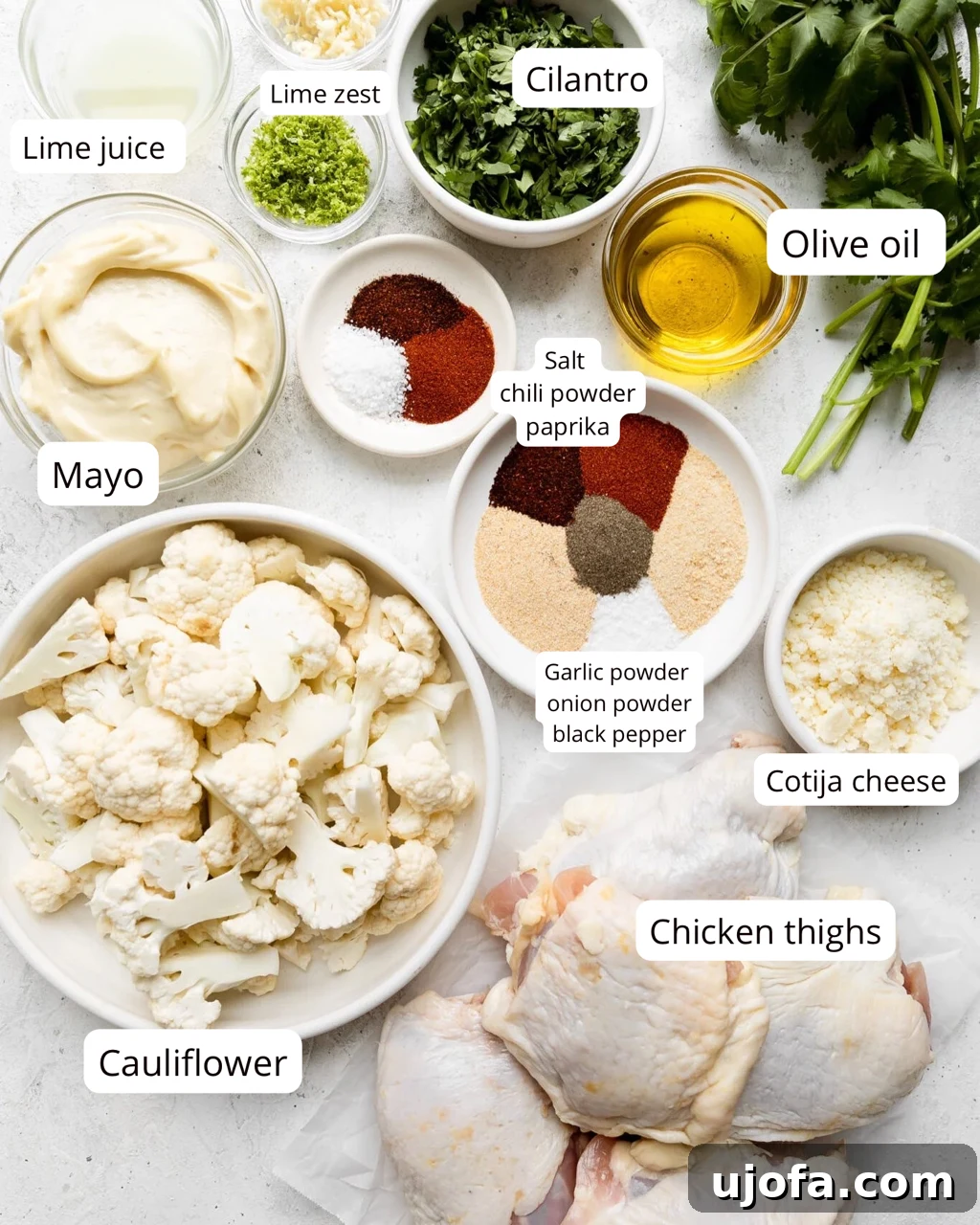 A vibrant display of ingredients for sheet pan street cauliflower and chicken thighs, showcasing fresh cauliflower florets, raw chicken thighs, and a rich spice blend in preparation.