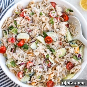 Healthy Tuna Pasta Salad in a white bowl with veggies and a white spoon