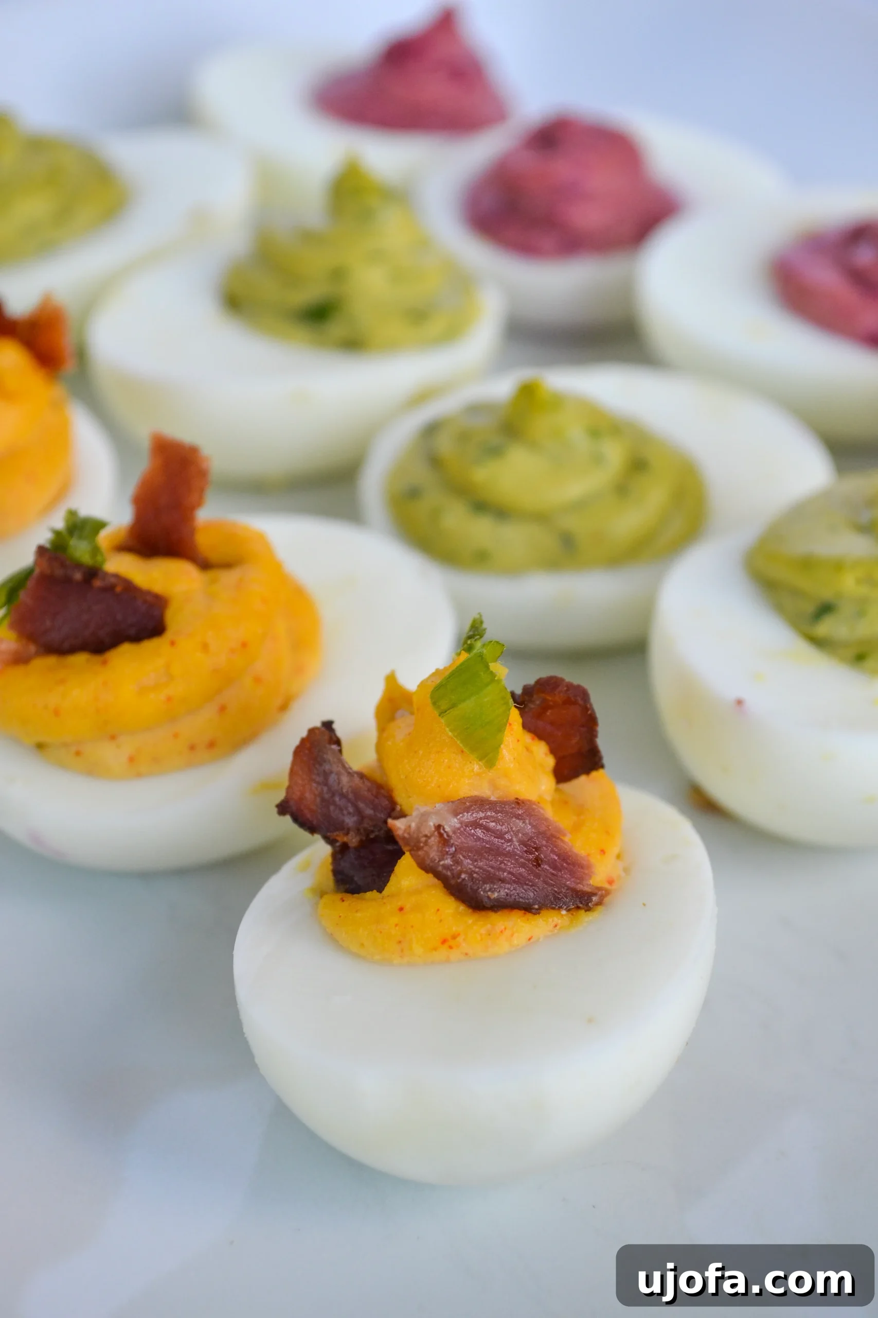 Three Tempting Deviled Egg Twists 2 A vibrant platter of Deviled Eggs 3 Ways, showcasing green avocado spinach, pink honey ginger beet, and classic bacon chive flavors, perfect for Easter.