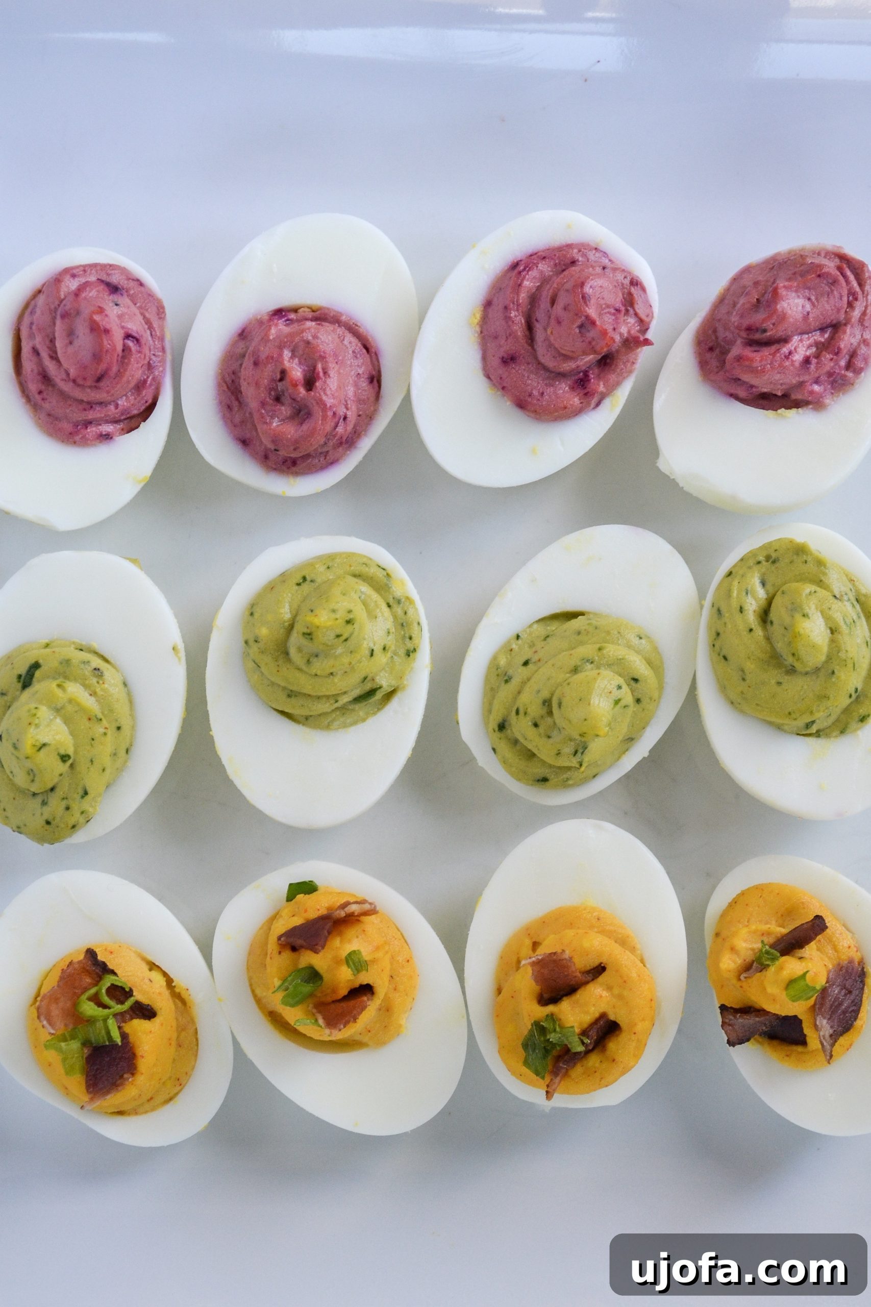 Three Tempting Deviled Egg Twists 4 A close-up of a serving platter filled with colorful deviled eggs, emphasizing the texture and garnishes of each unique flavor.