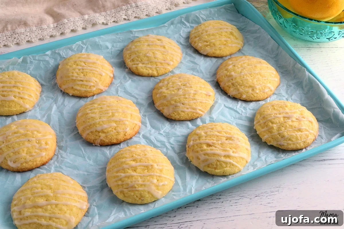 Effortless Gluten-Free Easter Sweets 14 Bright and zesty gluten-free lemon cookies arranged on a blue cookie sheet, with a bowl of fresh lemons providing a vibrant backdrop.