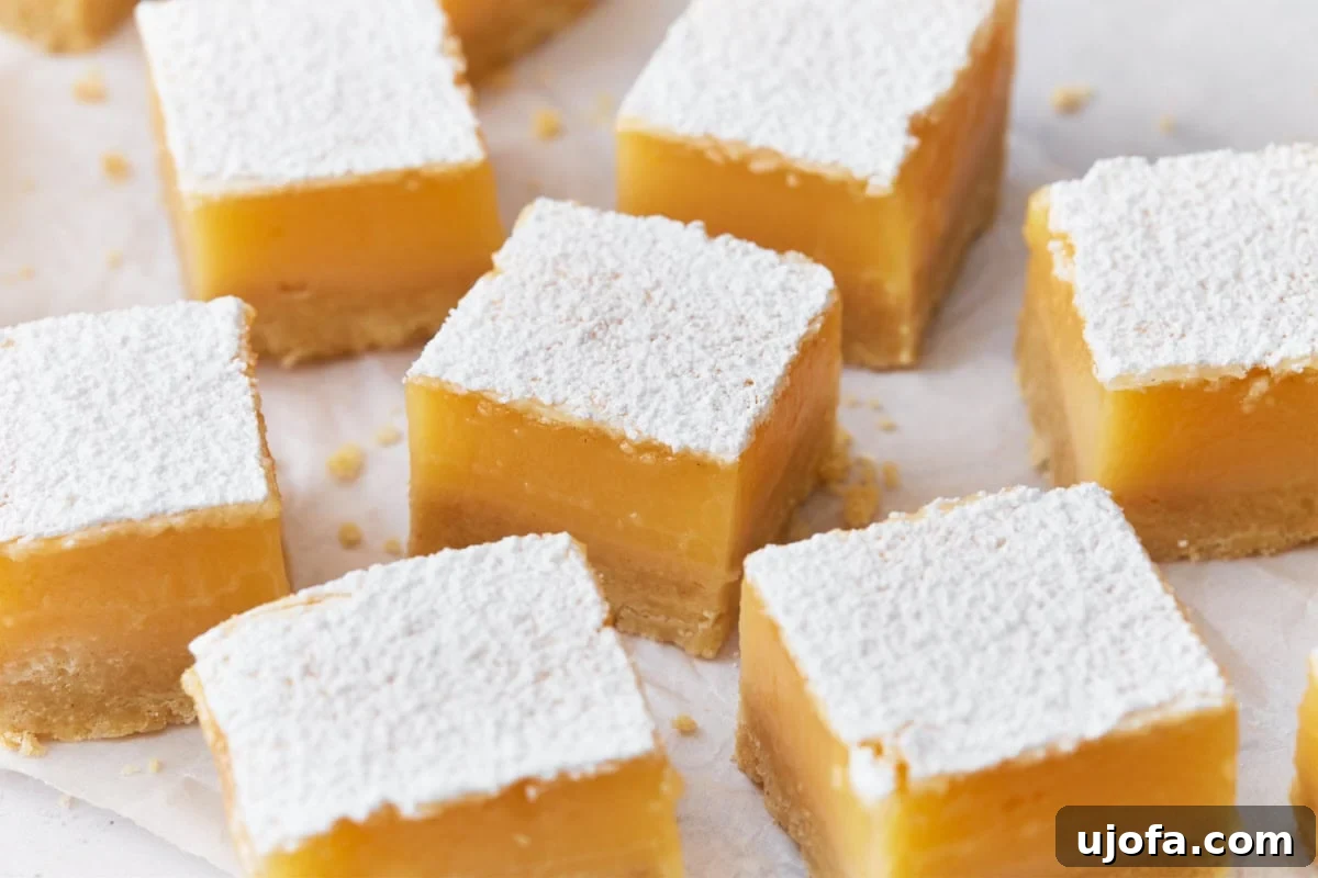 Effortless Gluten-Free Easter Sweets 6 Close-up of golden-baked gluten-free lemon bars, showcasing their thick, vibrant yellow lemon filling on a buttery shortbread crust, generously dusted with powdered sugar, arranged neatly on parchment paper.