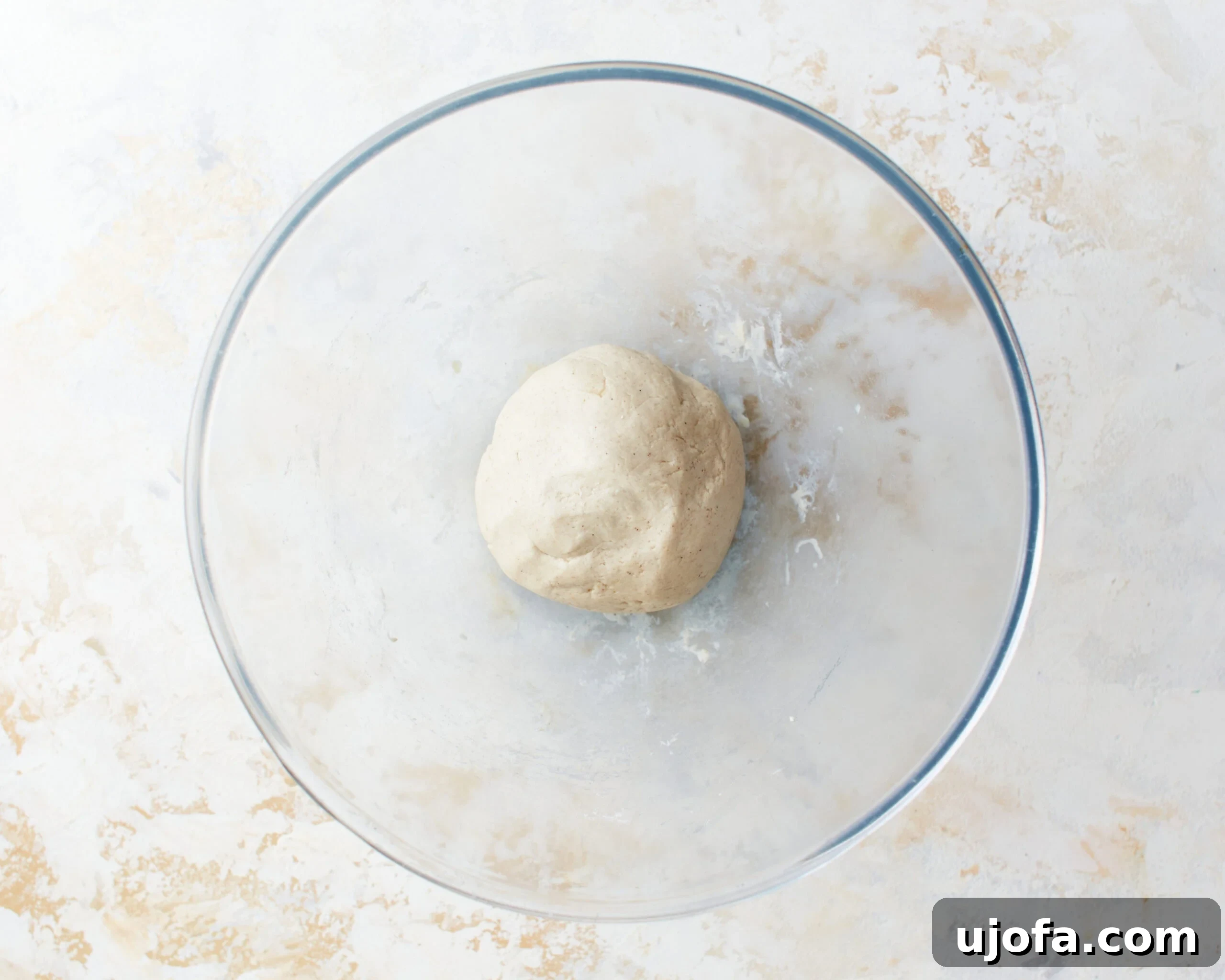 A smooth, perfectly formed ball of gluten-free tortilla dough resting in a glass mixing bowl, ready for the next stage of preparation.