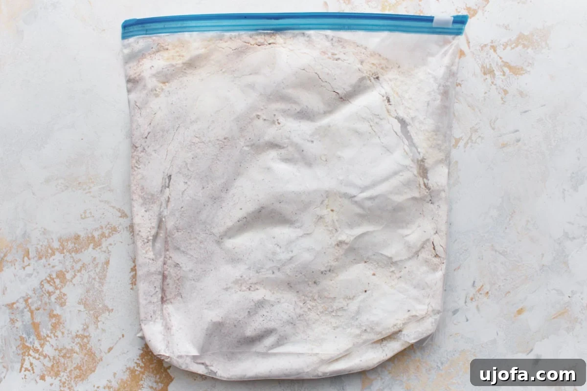 Gluten-free flour, cornstarch, and spice mixture in a large plastic bag laid flat on a light surface.