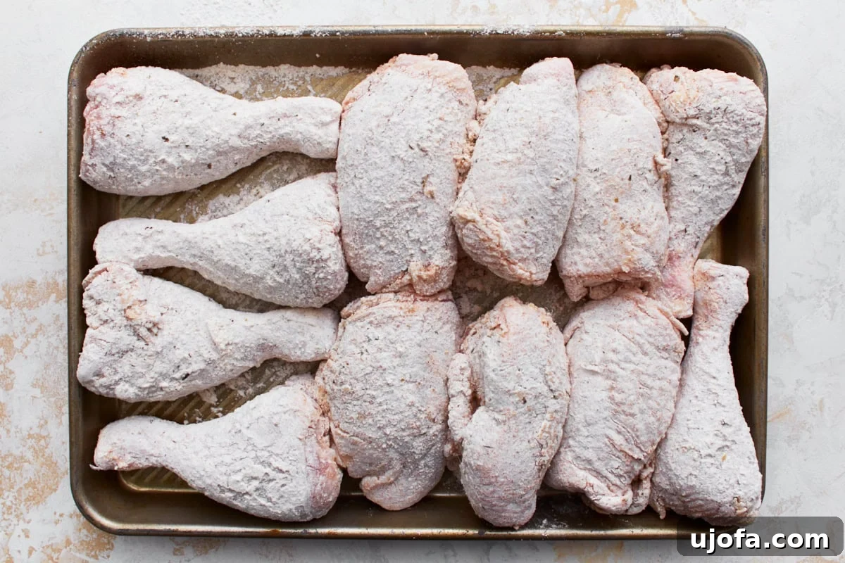 Gluten-free battered chicken thighs and drumsticks lined on a baking sheet