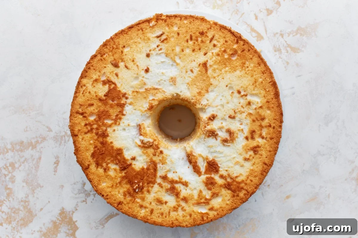 An inverted gluten-free angel food cake resting on a light countertop after being removed from the pan.