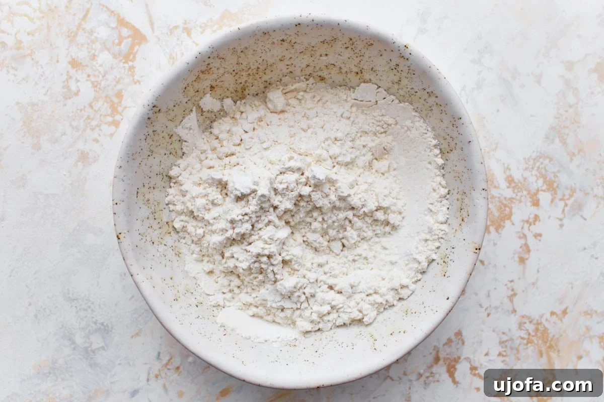 Gluten-free flour and cornstarch being mixed together in a white bowl.