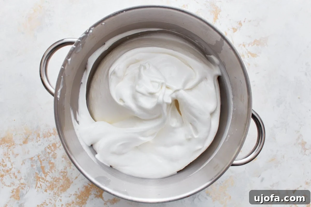 Smooth, whipped gluten-free angel food cake batter filling a stainless steel mixing bowl.