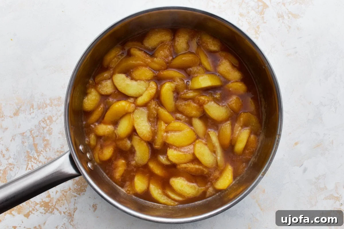 Heavenly Gluten-Free Peach Cobbler 5 A saucepan filled with freshly cooked peach filling, featuring golden peach slices coated in a rich, syrupy sauce, ready for the cobbler.