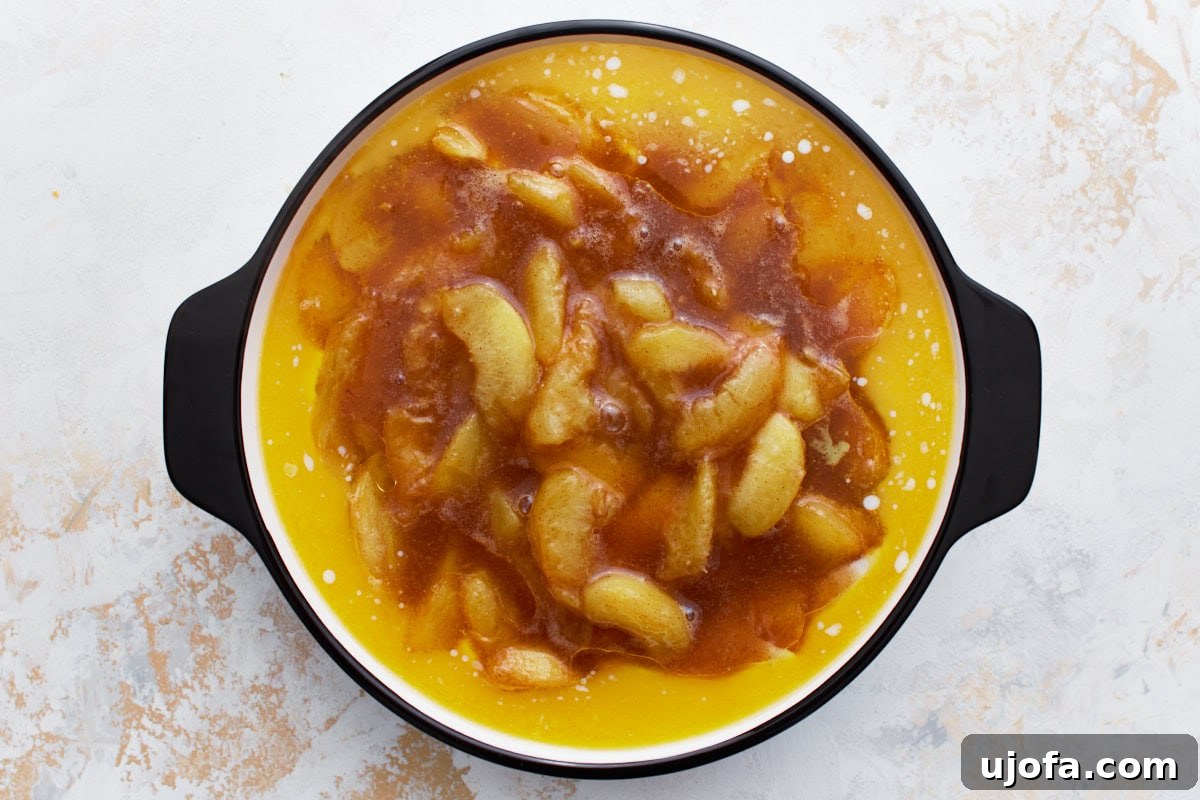 Heavenly Gluten-Free Peach Cobbler 9 A round baking dish with peach filling carefully placed on top of a smooth layer of cobbler batter and melted butter, prepared for baking.