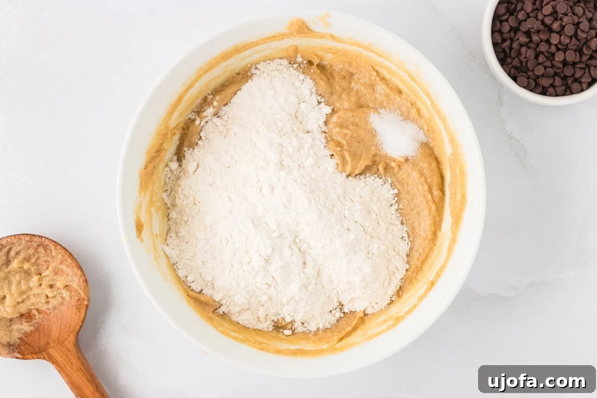Guilt-Free Gluten-Free Cookie Dough 7 Mixing bowl showing partially mixed cookie dough with gluten-free flour and salt added on top.