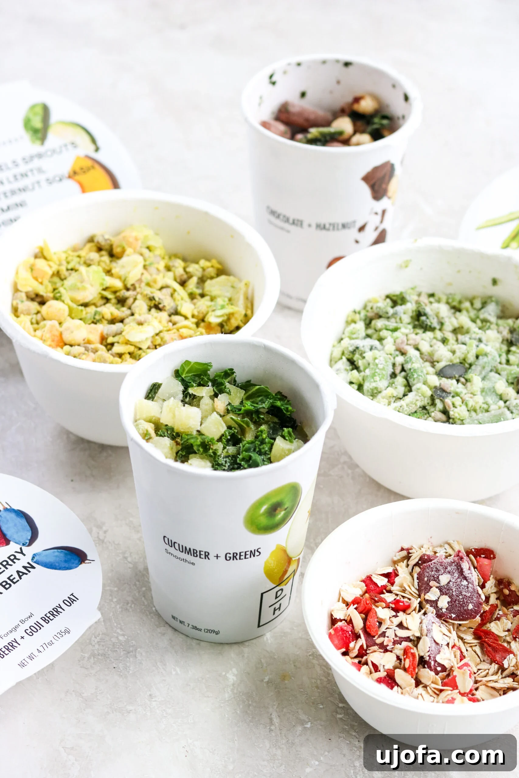 Daily Harvest smoothies and harvest bowls with their lids removed, showcasing the beautifully frozen, whole food ingredients inside.