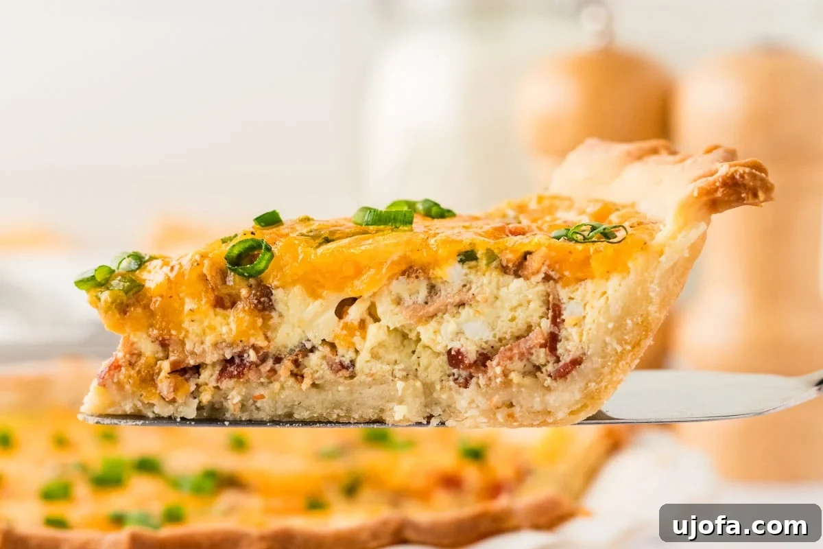 Ultimate Gluten-Free Quiche 14 A slice of gluten-free quiche being lifted from the pie dish, showcasing its perfectly flaky crust, rich, creamy filling, and visible layers of bacon and cheese. Fresh green onions provide a vibrant garnish.