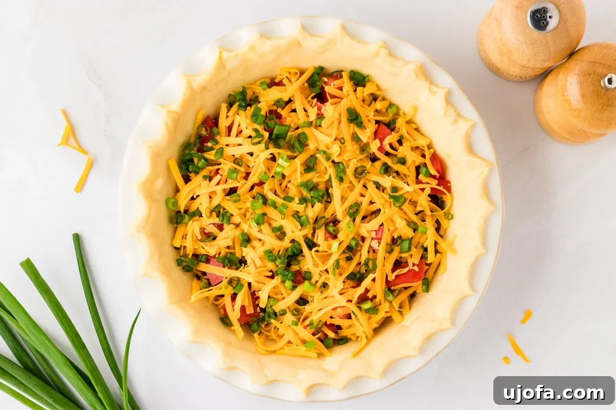 Ultimate Gluten-Free Quiche 8 The gluten-free quiche crust now holds layers of bacon, tomatoes, and a generous amount of shredded cheddar cheese, topped with freshly chopped green onions, ready for the liquid filling.
