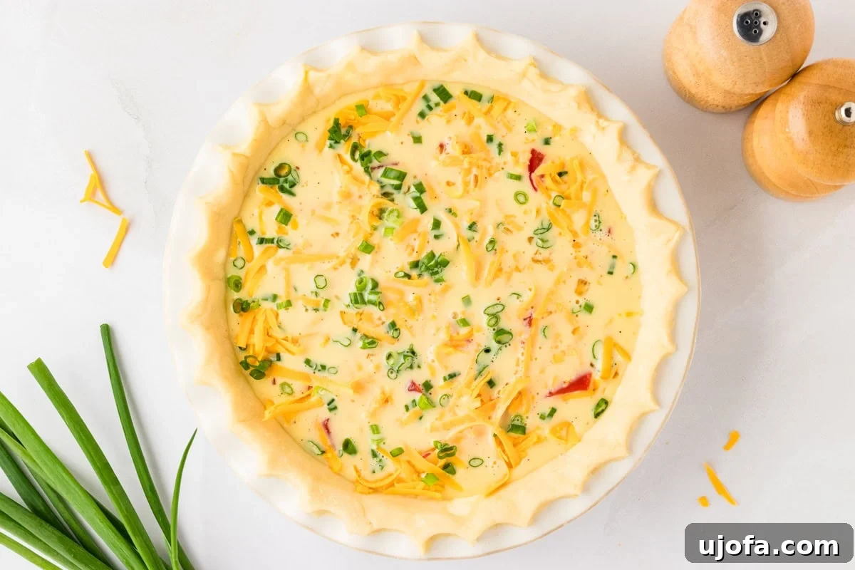 Ultimate Gluten-Free Quiche 9 A gluten-free quiche in its raw state, with the liquid egg mixture poured over the layers of cheese, bacon, and green onions, filling the pie crust before baking.