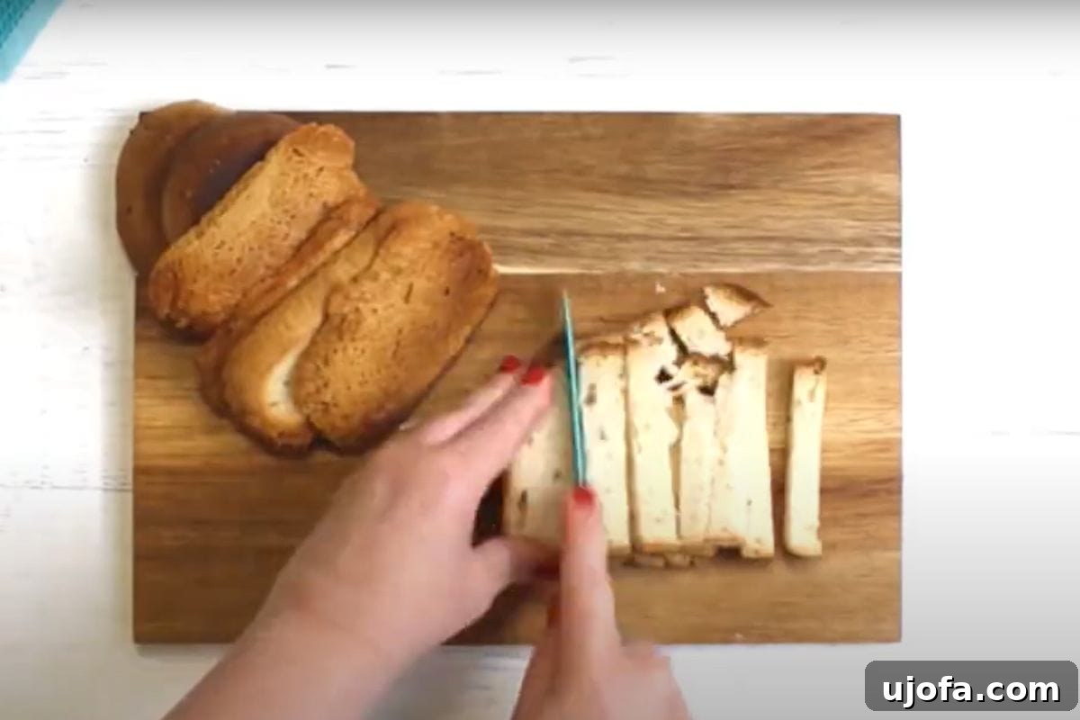 Crafting Delicious Gluten-Free Croutons 6 A hand slicing gluten-free bread on a chopping board into uniform cubes for making homemade croutons.