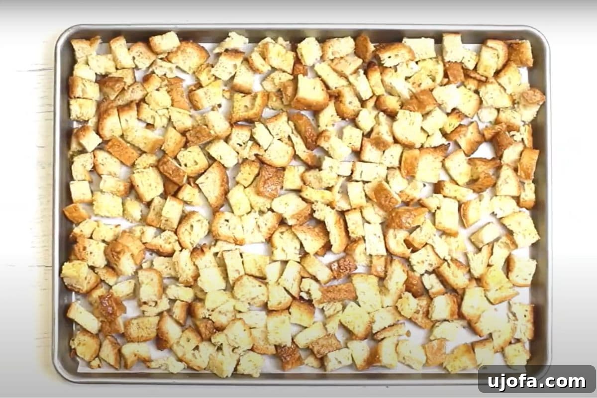 Crafting Delicious Gluten-Free Croutons 8 Seasoned gluten-free croutons meticulously spread in a single, uncrowded layer on a parchment-lined baking sheet, prepared for the oven.
